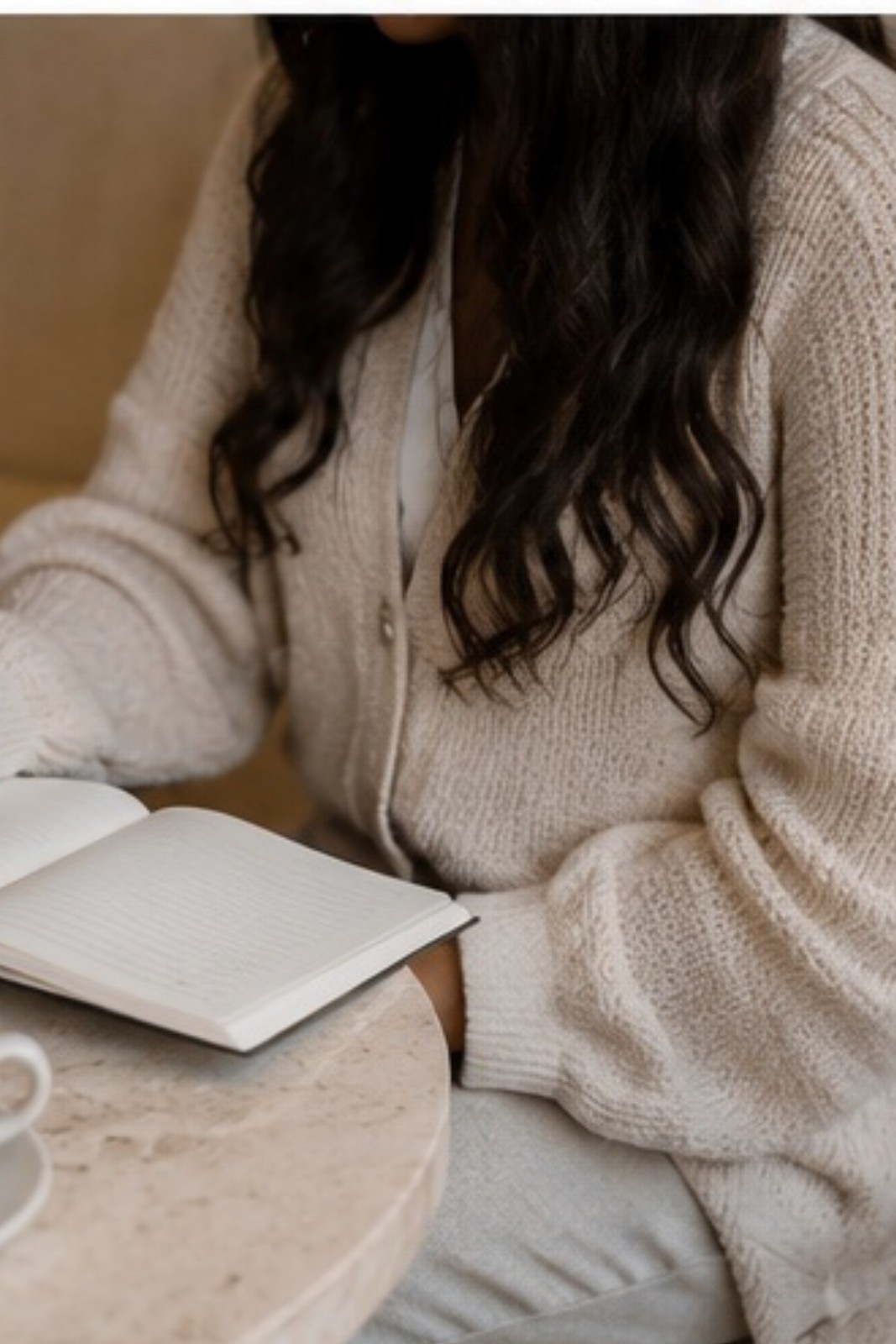 An open notebook and a cup of coffee on a marble table.